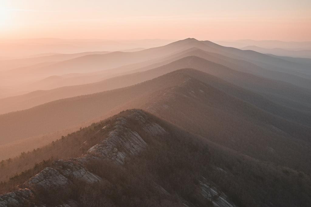 Photograph of a Blue Ridge mountain ridgeline at sunset with layered atmospheric haze, evoking the Charlottesville GSI Cost of Living Adjustment Rider and its compounding adjustments across decades of disability claims.
