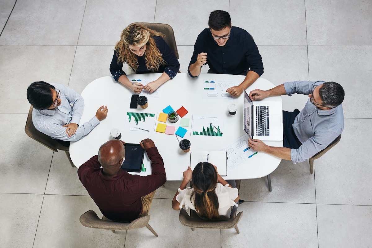 Small business owner-operators and multi-owner practice partners reviewing disability insurance carrier comparison reports from Guardian, Principal Financial Group, MassMutual, Ameritas, and The Standard at a conference table